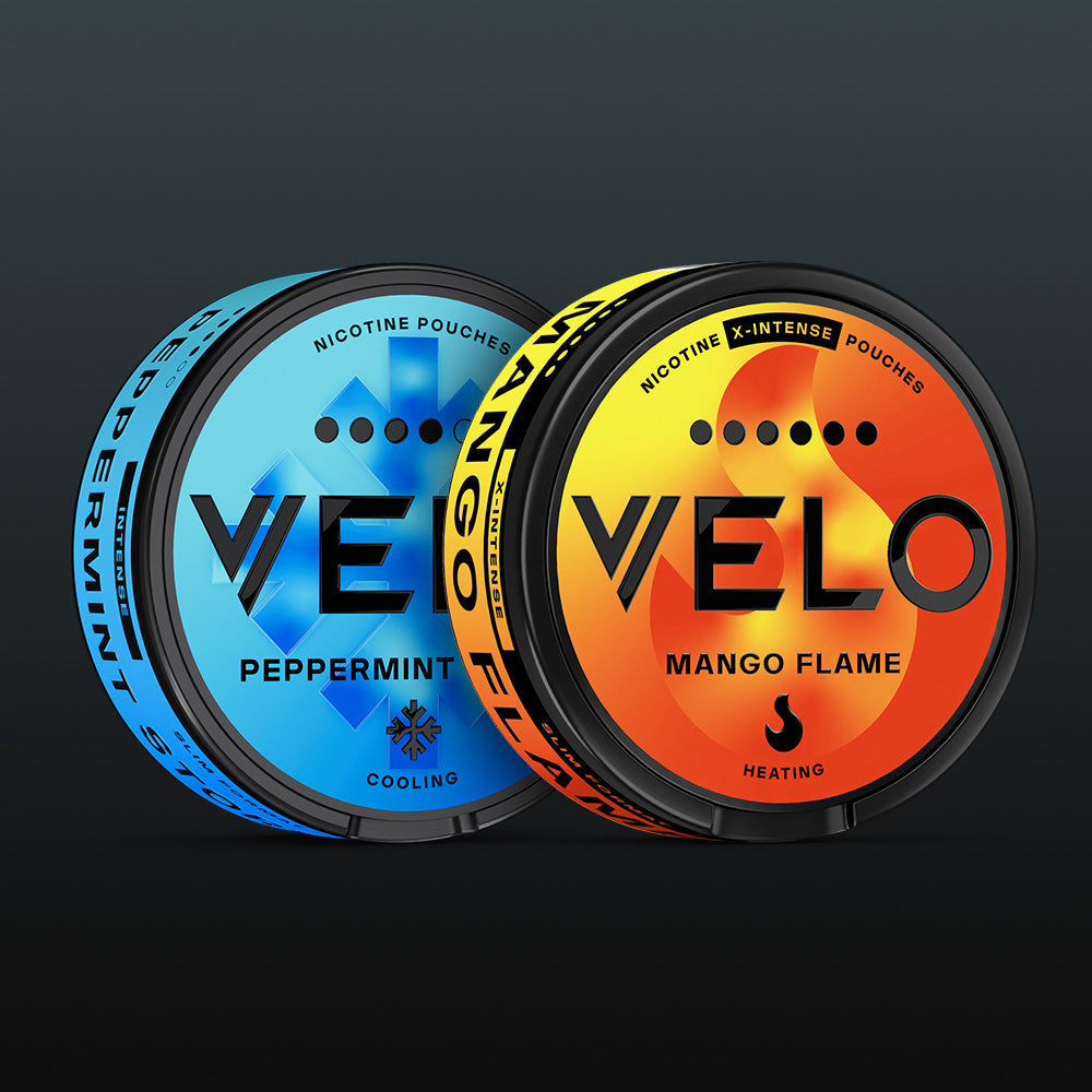Velo Nicotine Pouches |  Two round VELO nicotine pouch containers—one blue labeled Peppermint, one orange labeled Mango Flame—are displayed side by side. Both pouches feature bold Velo branding and vibrant, flavor-focused graphic accents set against a dark background.