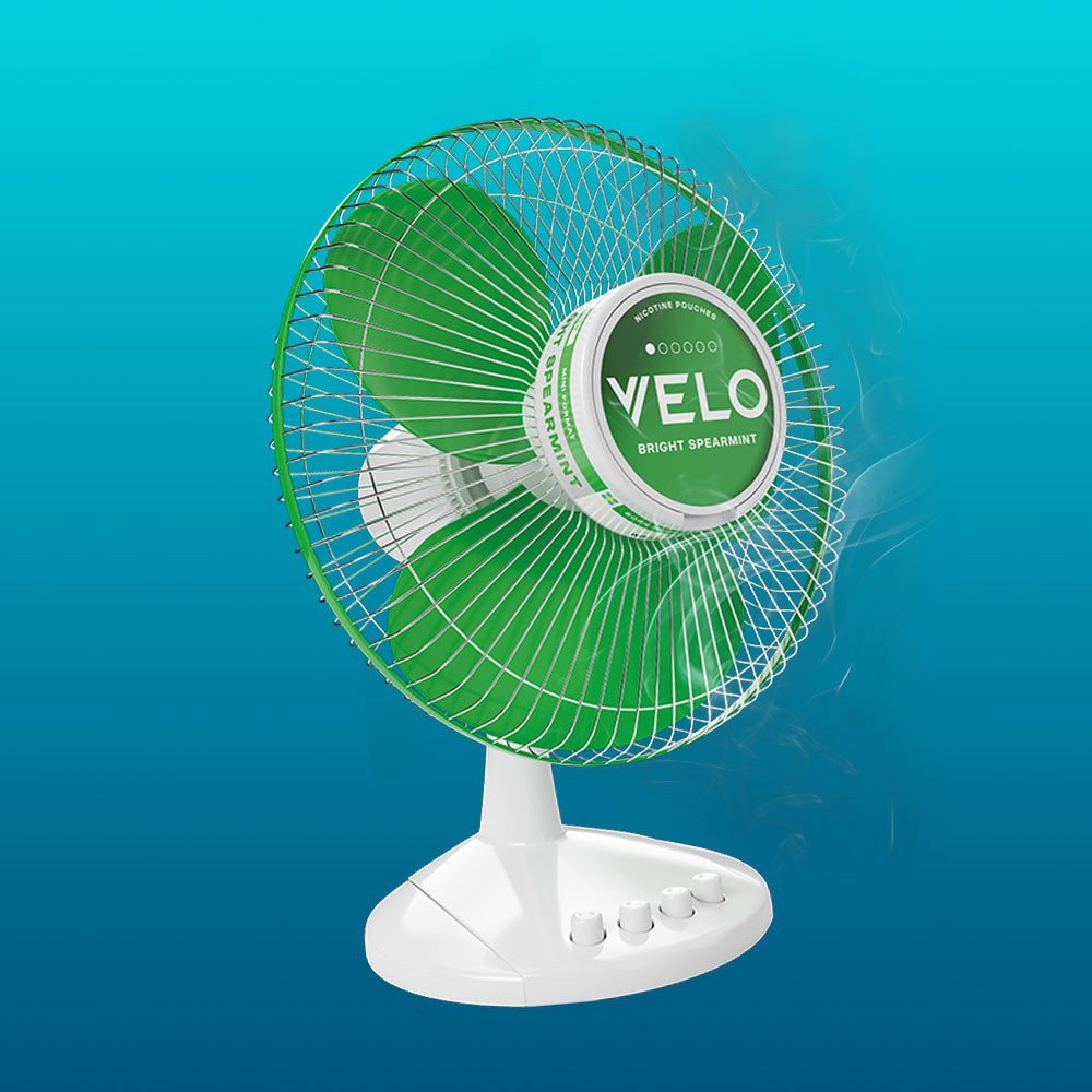 Velo Nicotine Pouches |  A green and white electric fan with VELO on the center, emitting a mist of cool air, is set against a blue gradient background, evoking the refreshing sensation of Velo nicotine pouches.