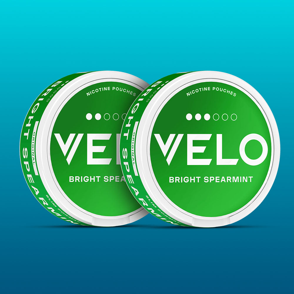 Velo Nicotine Pouches |  Two green round cans labeled VELO Bright Spearmint Nicotine Pouches are shown overlapping against a blue gradient background, highlighting the fresh appeal of these Velo nicotine pouches.