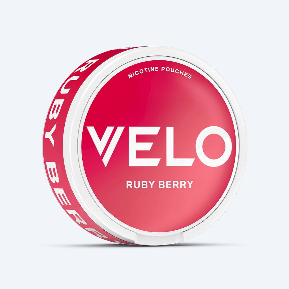 Velo Nicotine Pouches |  A round white container with a vibrant pink lid labeled VELO and Ruby Berry, containing nicotine pouches with a strawberry blend and acidic notes. "Ruby Berry" is also displayed in white text on the container's side.