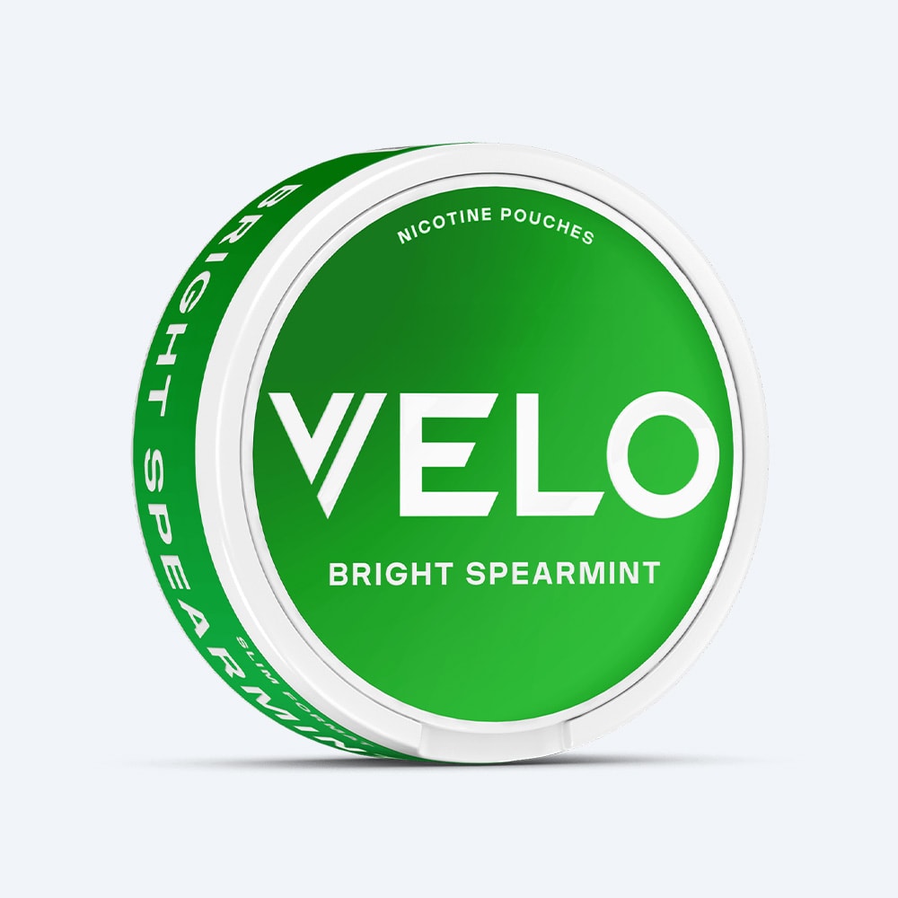 Velo Nicotine Pouches |  A round white container featuring a green label with the text "VELO Bright Spearmint" Nicotine Pouches, offering a refreshing blend of spearmint and cool menthol sensations.