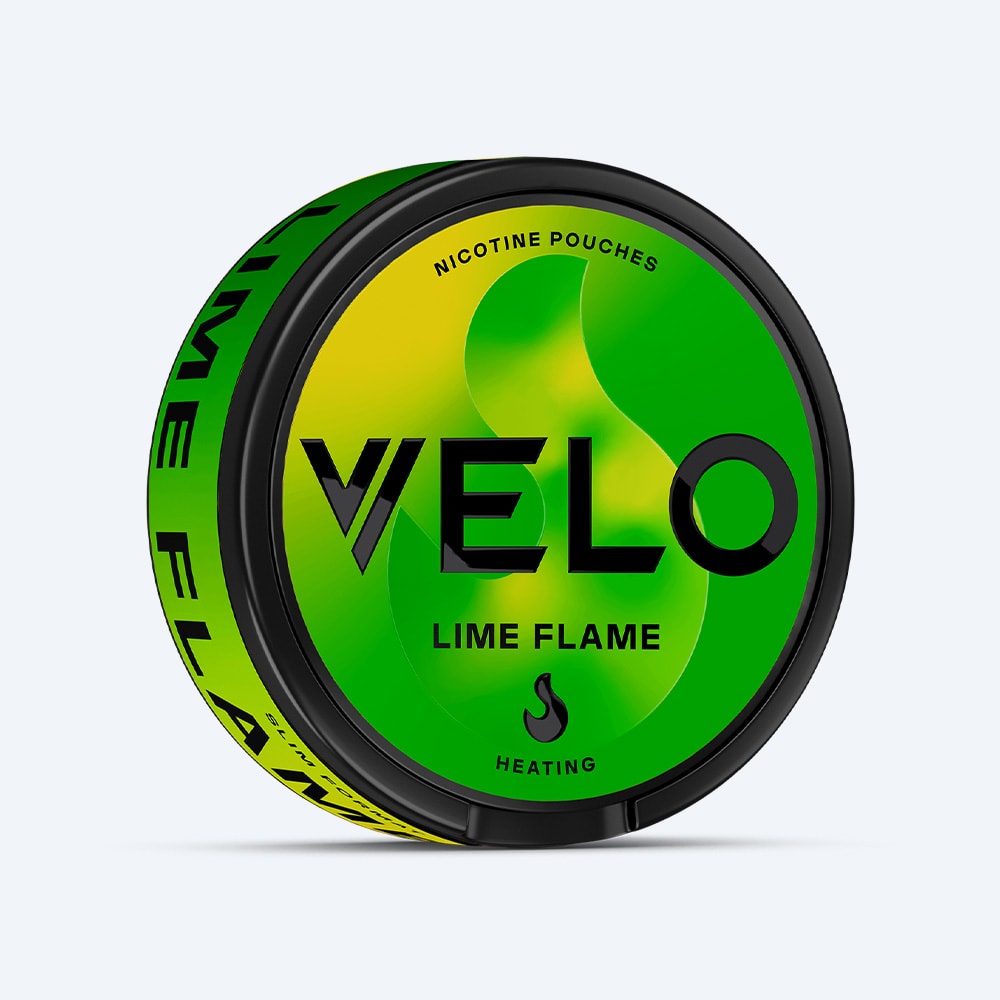Velo Nicotine Pouches |  A round container of VELO Lime Flame nicotine pouches features a green and yellow design. The front label displays the words "LIME FLAME" and "HEATING," reflecting the bold blend of zesty lime and aromatic jalapeno flavors inside.