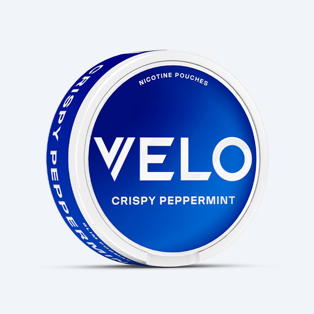 Velo Nicotine Pouches |  A round tin in blue and white, branded with the VELO logo and labeled "Crispy Peppermint," features "Nicotine Pouches" above the logo. The side of the tin also displays "Crispy Peppermint," emphasizing VELO’s signature refreshing peppermint flavor and cooling aftertaste.