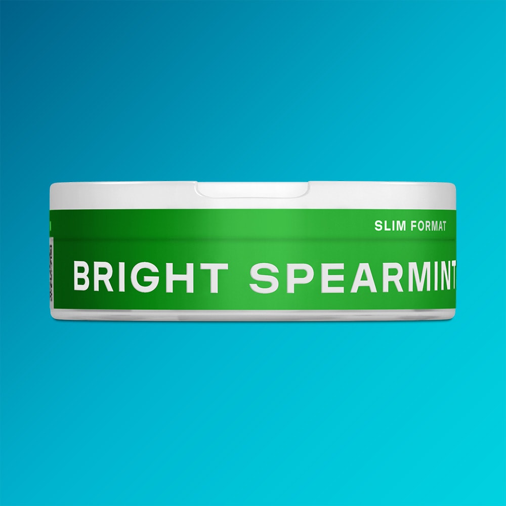 Velo Nicotine Pouches |  A white, round container featuring a green label displays the brand name VELO and the product name Bright Spearmint in slim format, suggesting refreshing hints of spearmint and menthol, all set against a blue background.