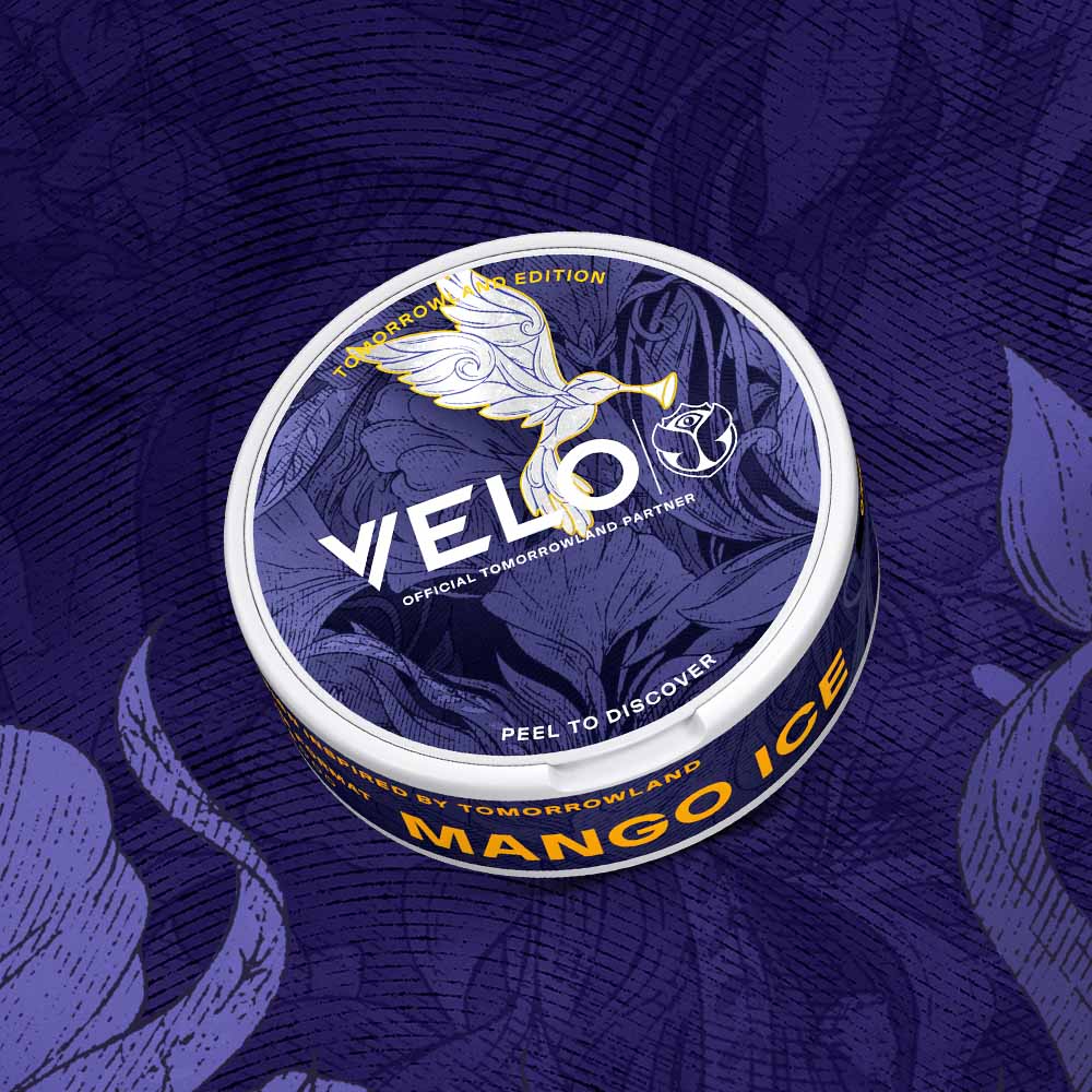 Velo Nicotine Pouches |  A round container of VELO Mango Ice nicotine pouches, featuring a white dove design and labeled as the Tomorrowland Edition, sits on a purple, patterned surface. This sleek pack of VELO pouches combines style and flavor for an elevated nicotine experience.