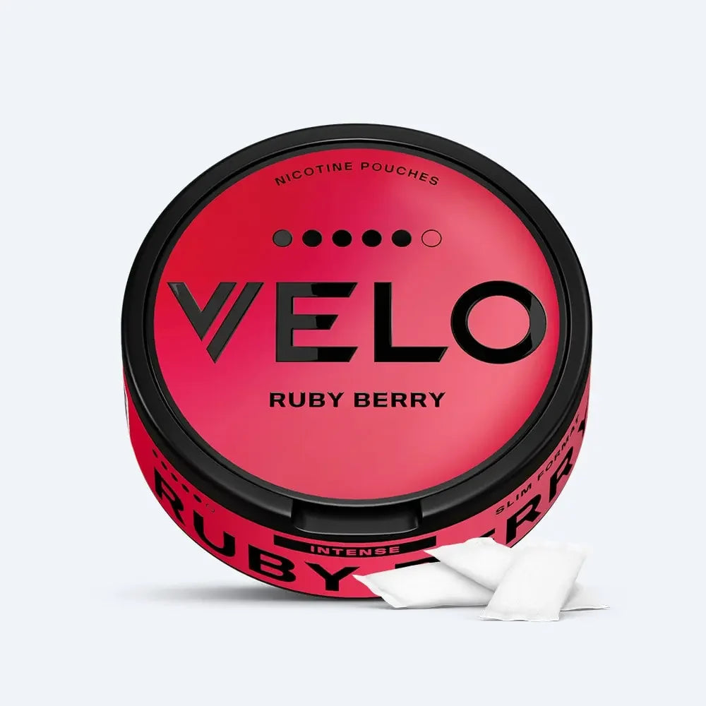 Velo Nicotine Pouches |  A round container labeled VELO Ruby Berry pouches, with a berry-colored gradient design. Two white nicotine pouches are placed in front of the container, highlighting the sleek and modern presentation of Velo's nicotine products.